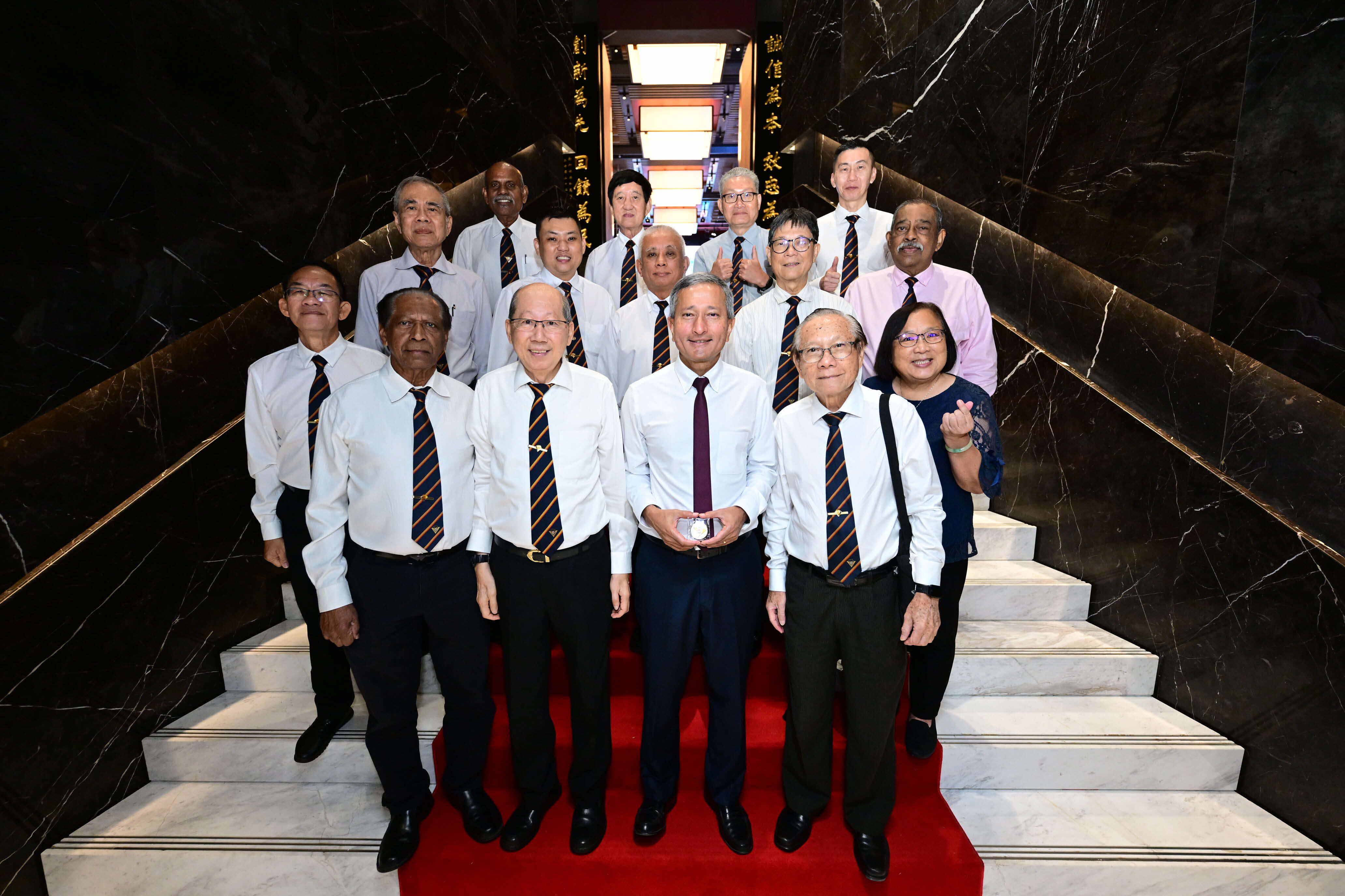 Two men in suits shake hands before flags of Singapore, Austria, and the European Union.